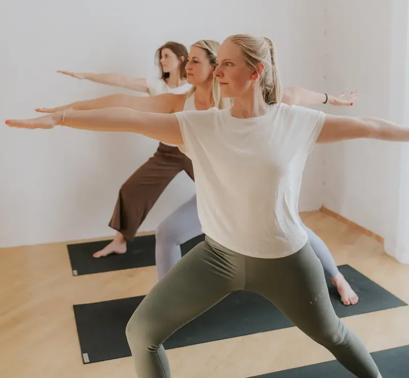 Gruppe im Yogastudio in der Kriegerhaltung